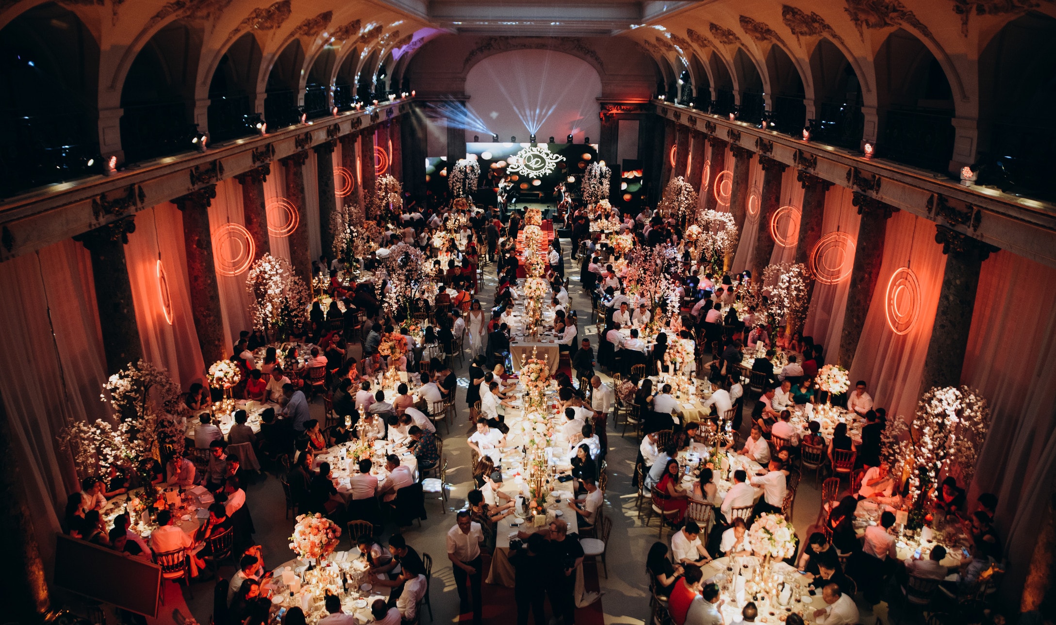 A banquet hall full of round dinner tables, seen from the gallery