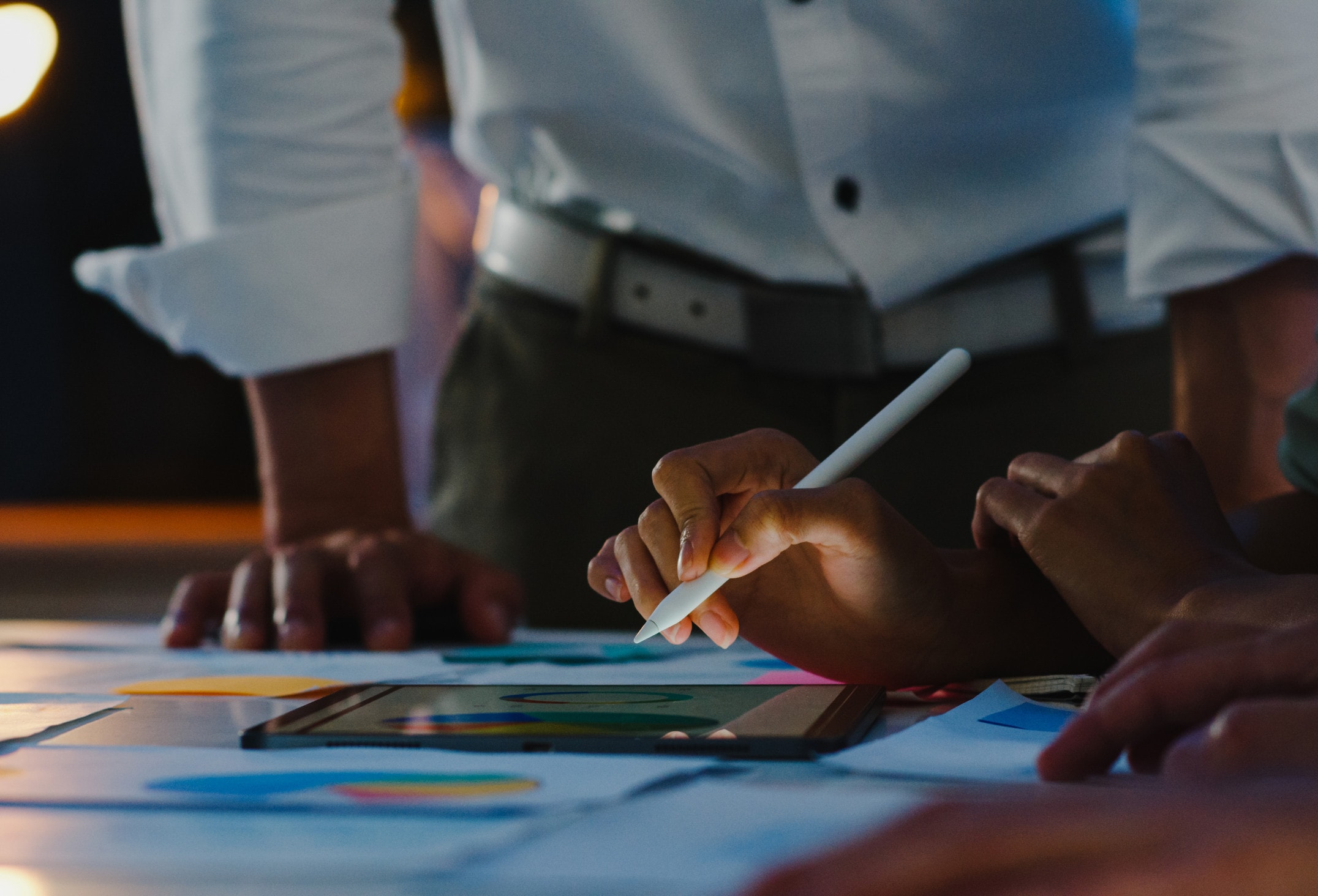 A team marking up printed charts with a stylus and a tablet